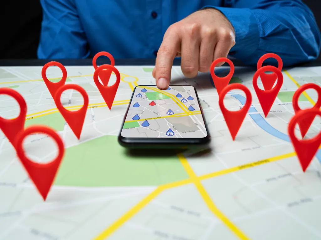 Smartphone on a map surrounded by location pins, representing local SEO, business listings, and geographic search visibility