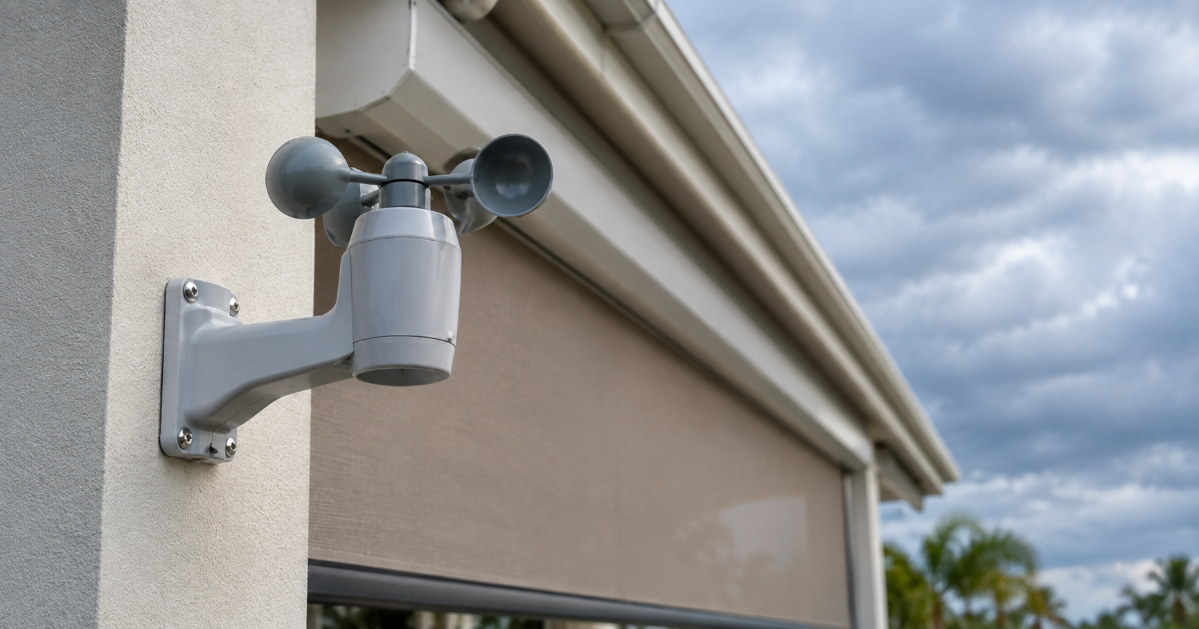 Close-up of a wind sensor mounted near a motorized Fenetex screen housing on a Northwest Florida patio.