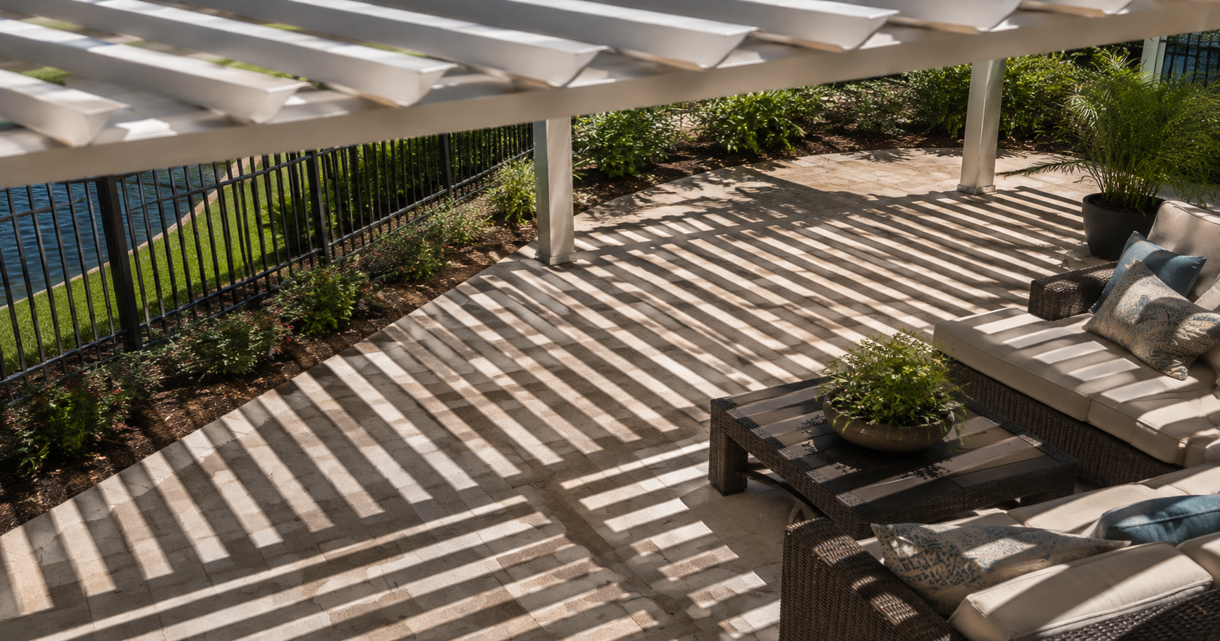 Aluminum pergola casting dappled shade patterns on a Northwest Florida patio, illustrating slat spacing and sun angle.