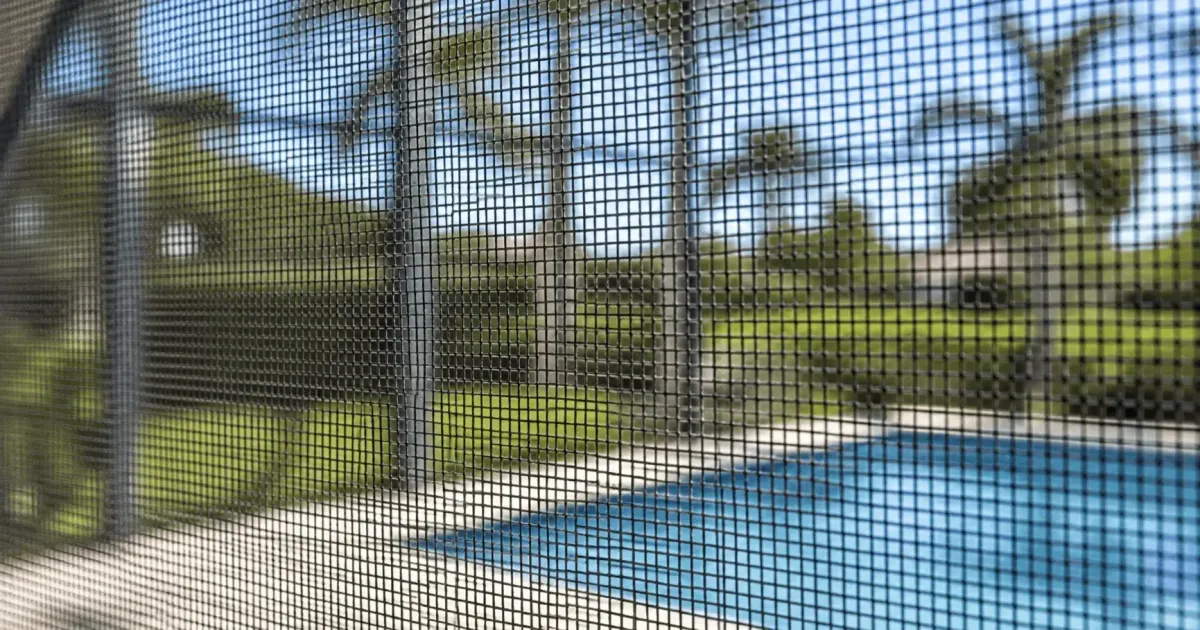 Close-up of fine pool screen mesh with a poolside view through the enclosure in Milton, Florida by Aluminum Building Systems