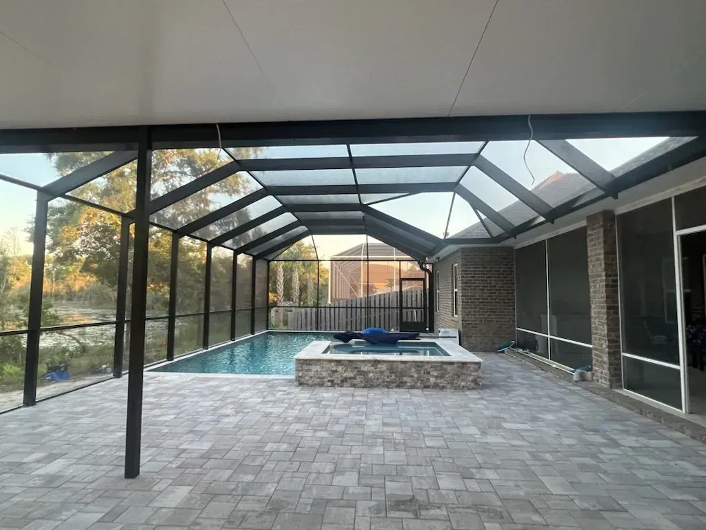 Bronze mansard enclosure screening a pool, raised spa, and paver deck, installed by Aluminum Building Systems in Freeport, FL