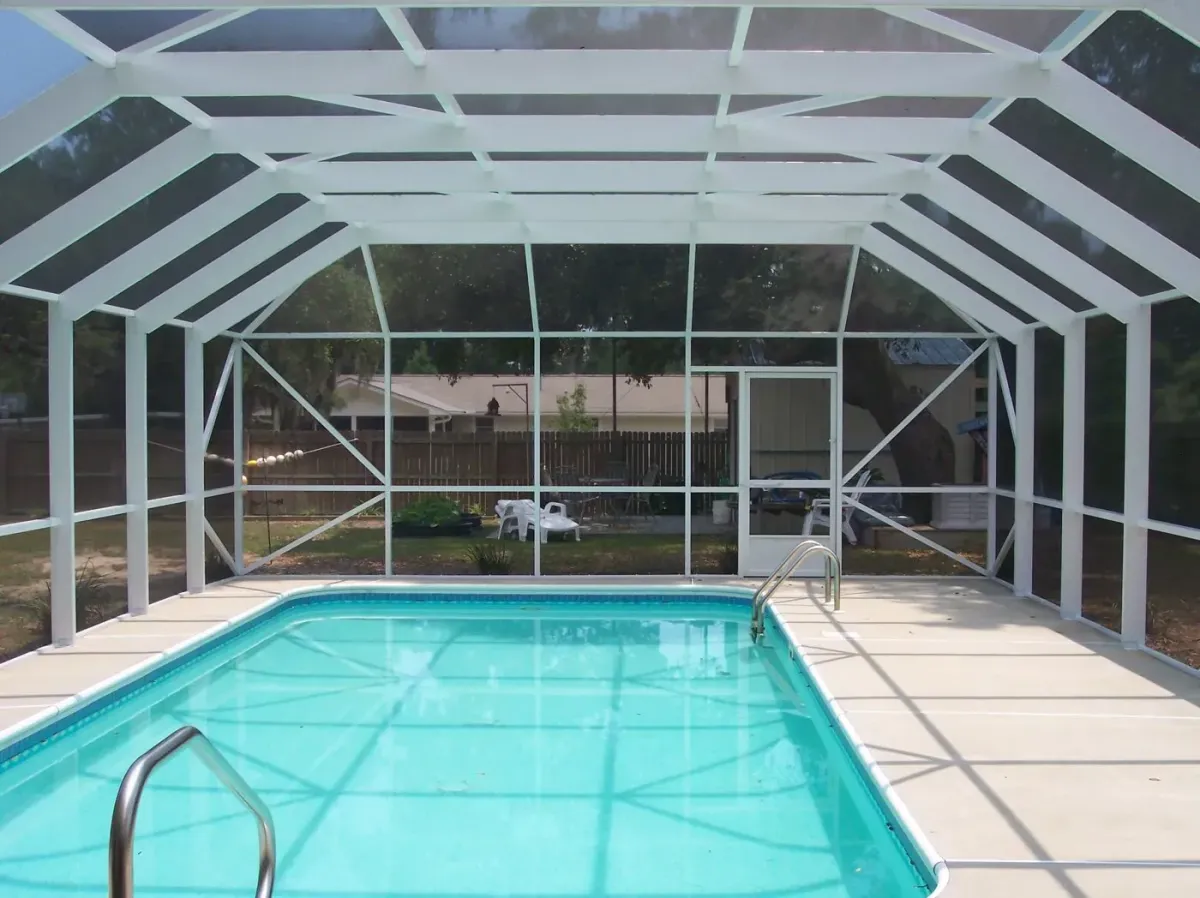 White aluminum mansard pool enclosure with a flat center roof over a screened pool, built by Aluminum Building Systems in Gulf Breeze, FL