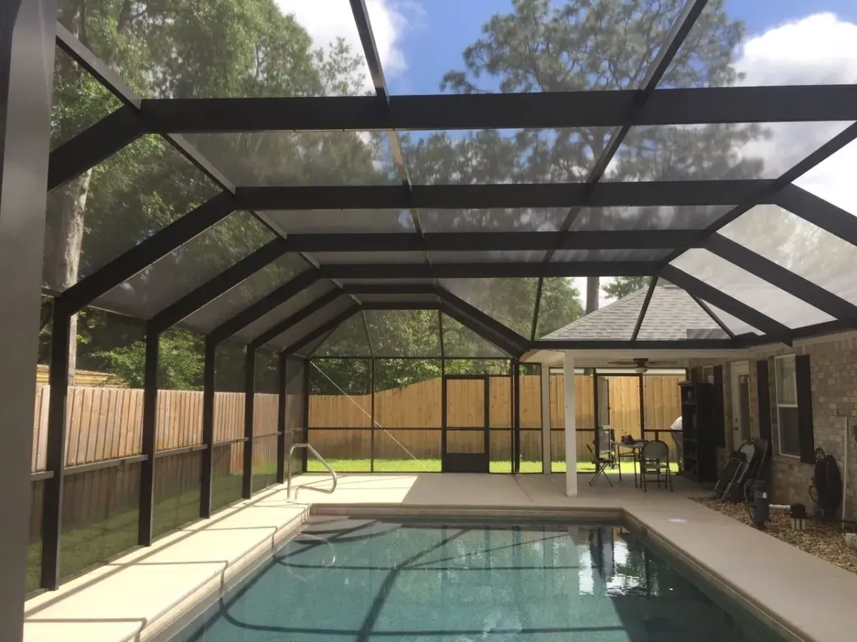 Inside a bronze mansard pool enclosure, flat center roof sloping to screen walls, built by Aluminum Building Systems in Niceville, FL