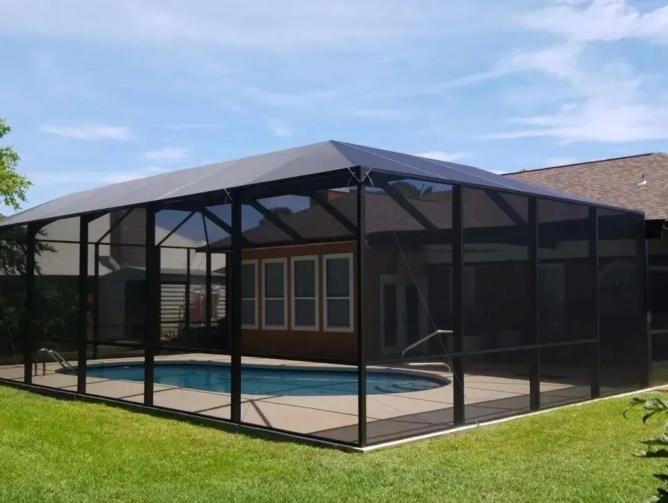 Low-profile bronze mansard screen enclosure behind a ranch-style home, built by Aluminum Building Systems in Crestview, FL