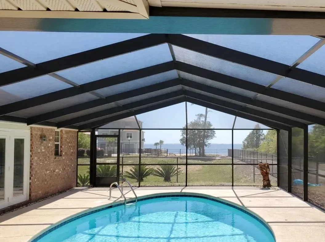 Bronze gable pool enclosure with its gable end facing the water over a blue pool, installed by Aluminum Building Systems in Inlet Beach, FL