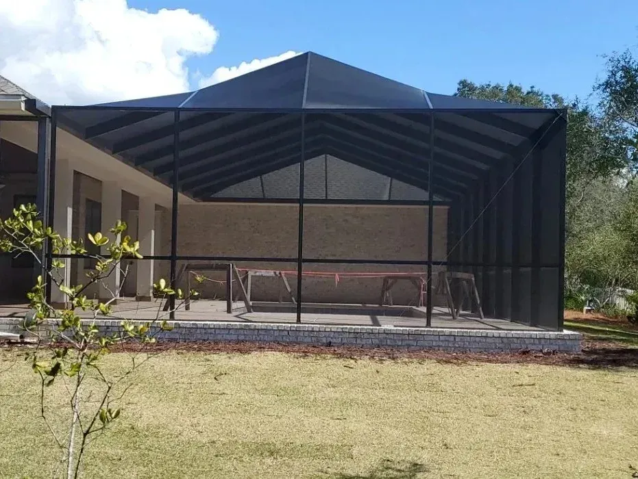 Bronze peak roof pool screen enclosure seen from the backyard lawn, built by Aluminum Building Systems in Milton, FL