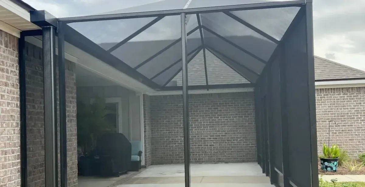 Finished bronze lazy hip pool enclosure beside a two-story brick home, built by Aluminum Building Systems in Panama City Beach, FL