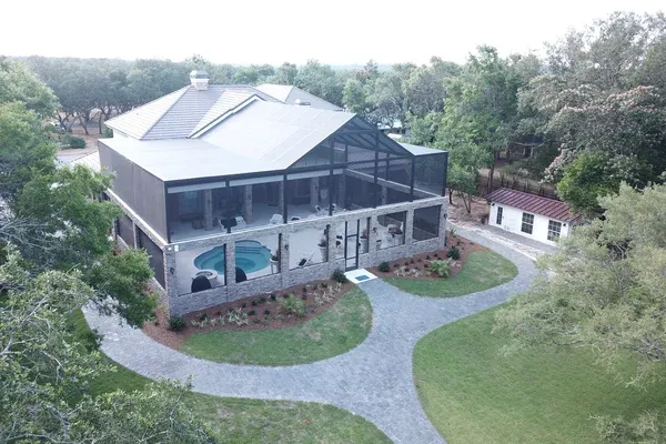 Aerial view of a two-story screened pool enclosure with a stone knee wall, built by Aluminum Building Systems