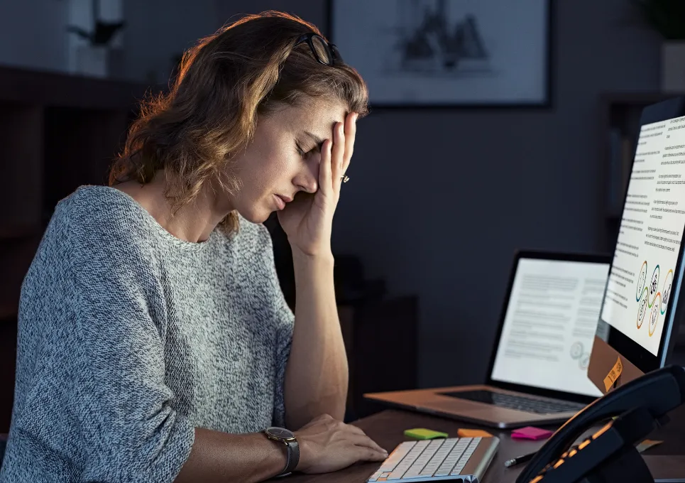 Woman looking sad while sat at a computer with her head in her hands