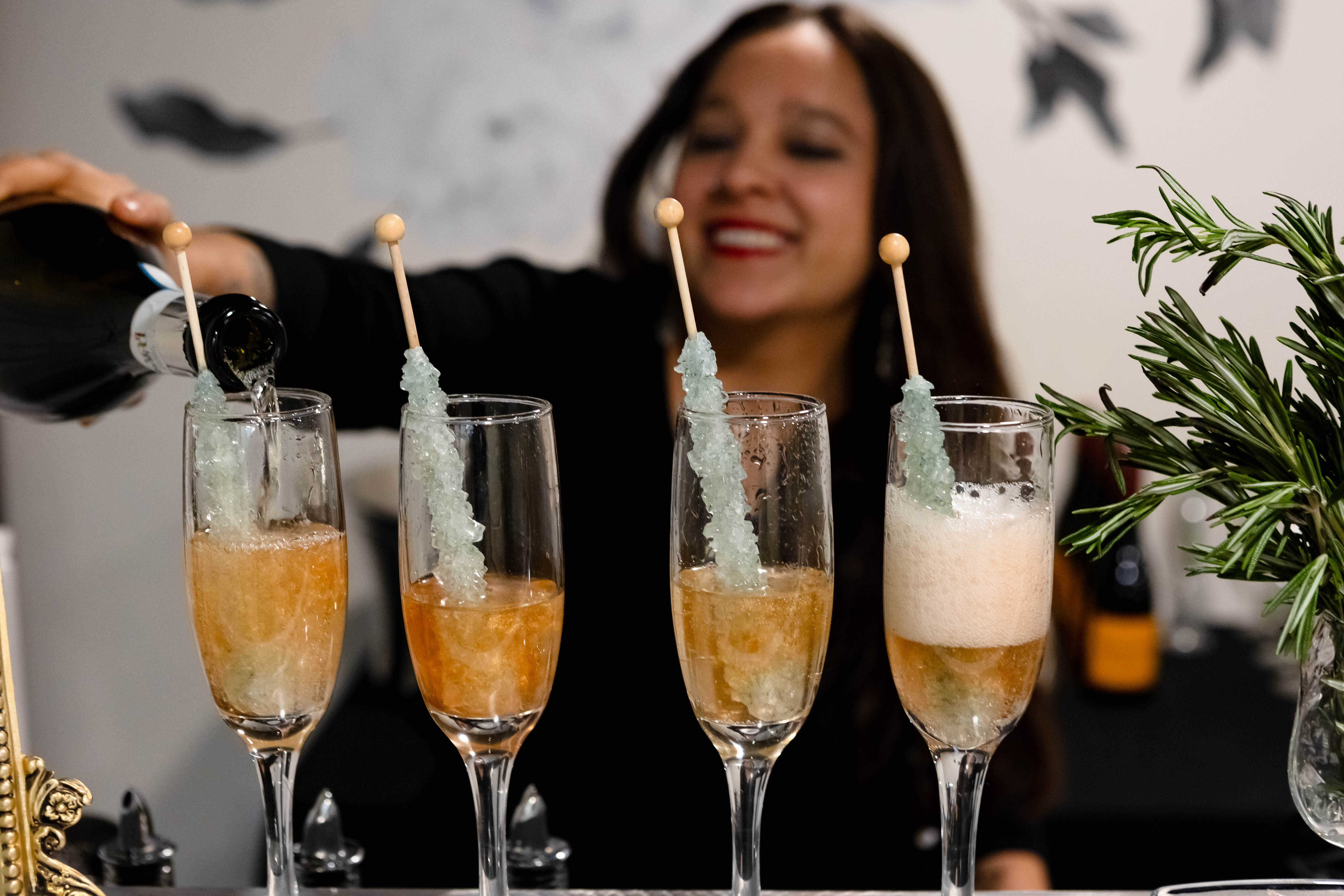 Bars on Wheels bartender pouring champagne cocktails with rock candy garnish.