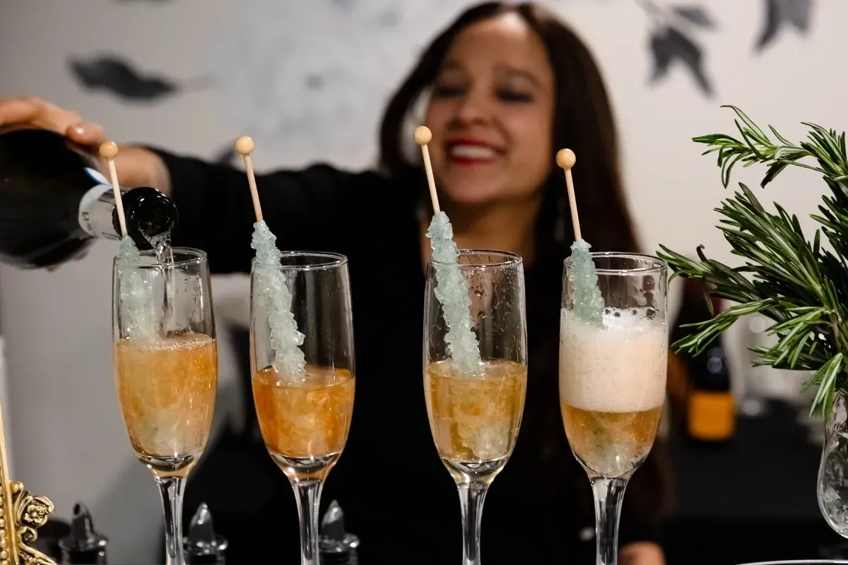 Bars on Wheels bartender pouring champagne cocktails into glasses at elegant private event bar setup