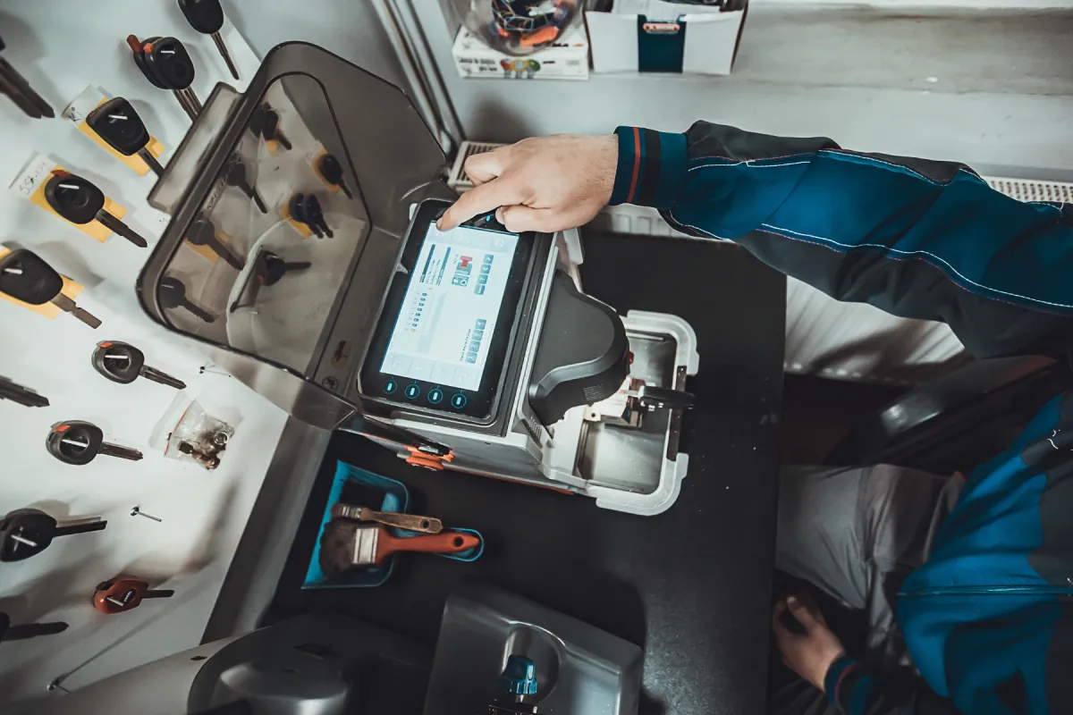 Locksmith cutting car key with his machine