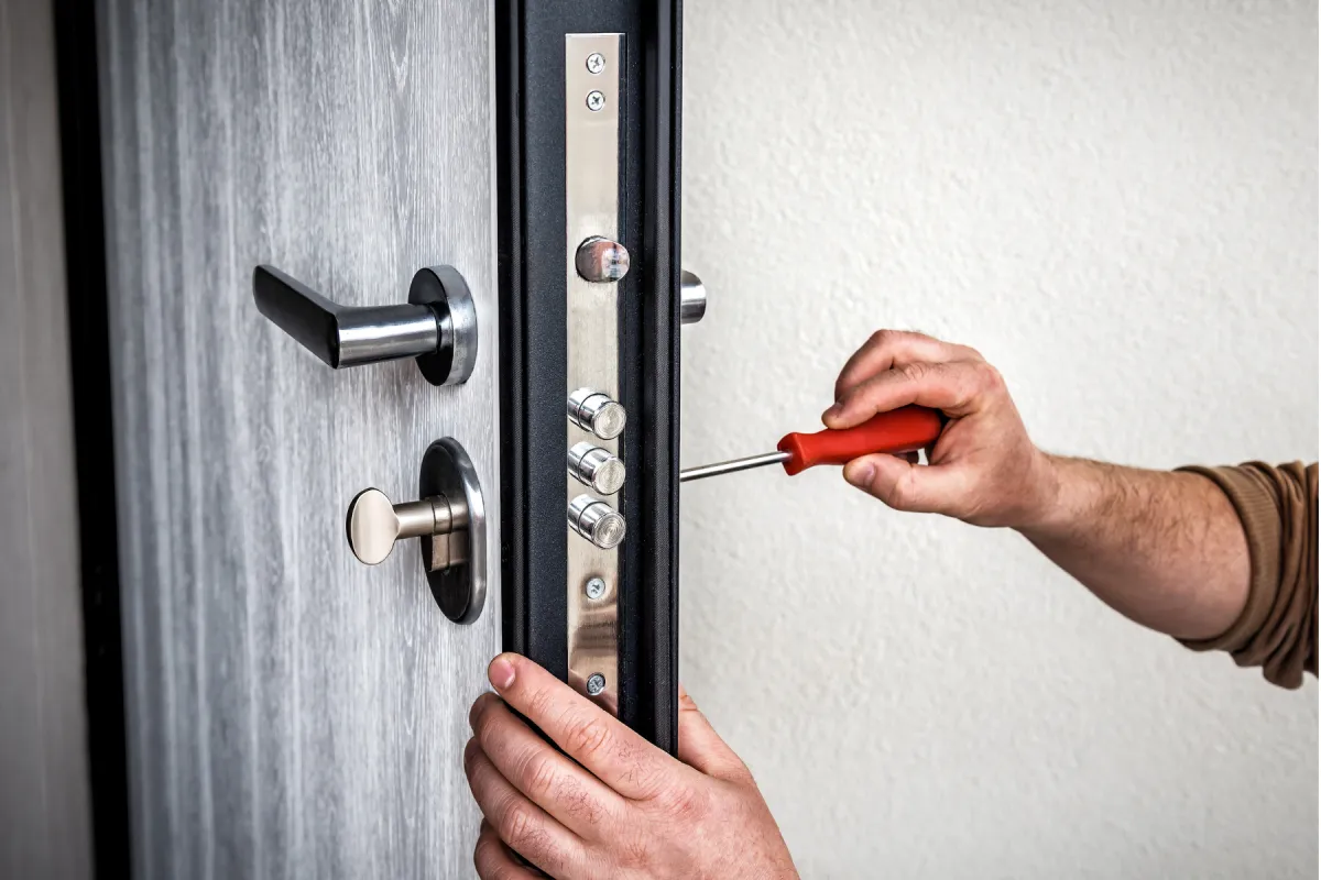 Handyman repair the door lock in metal entrance door, Man fixing lock with screwdriver