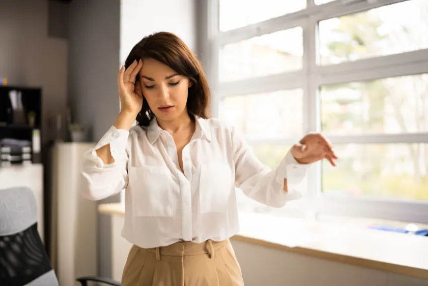 Woman experiencing dizziness and balance issues while holding her head for support.