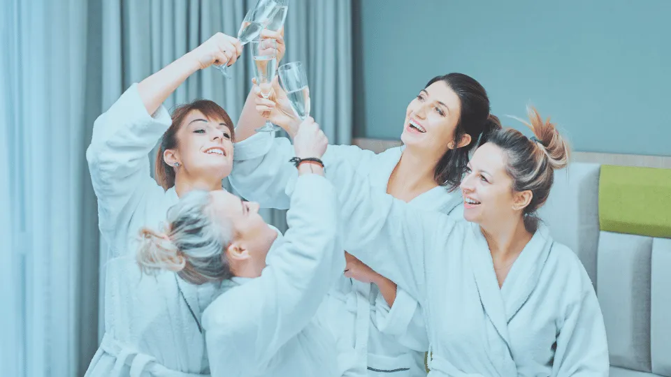 Four happy friends in robes smiling after their spa treatments