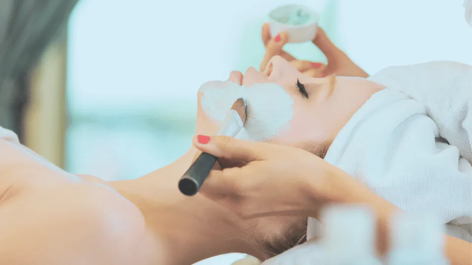 A woman getting a facial face mask added