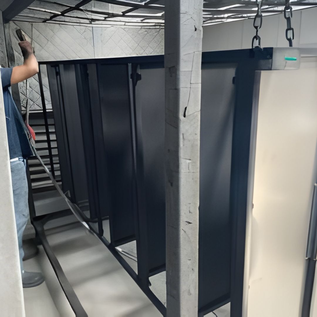 Metal panels hanging on a conveyor system inside a powder coating or finishing facility.