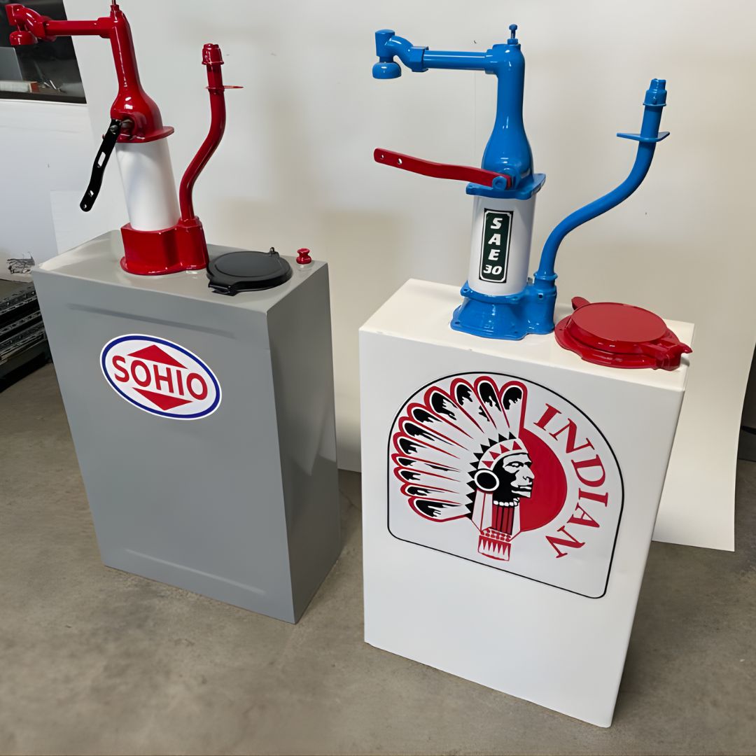 Two restored antique dispensers are showcased: one in gray with a "Skelly" logo and another in white with an "Indian" logo and a bright blue pump handle.