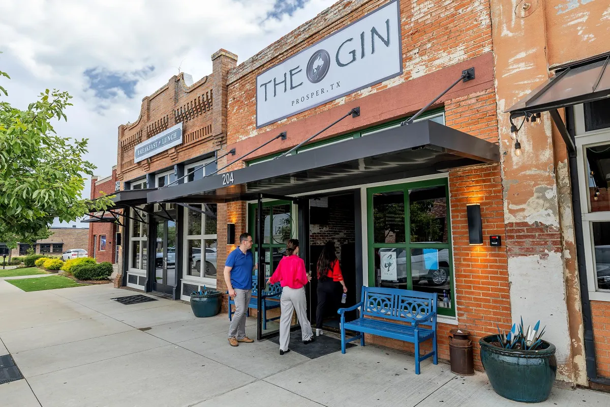 Exterior view of The Gin restaurant in Prosper, Texas, with patrons entering, showcasing a welcoming atmosphere and local business charm.