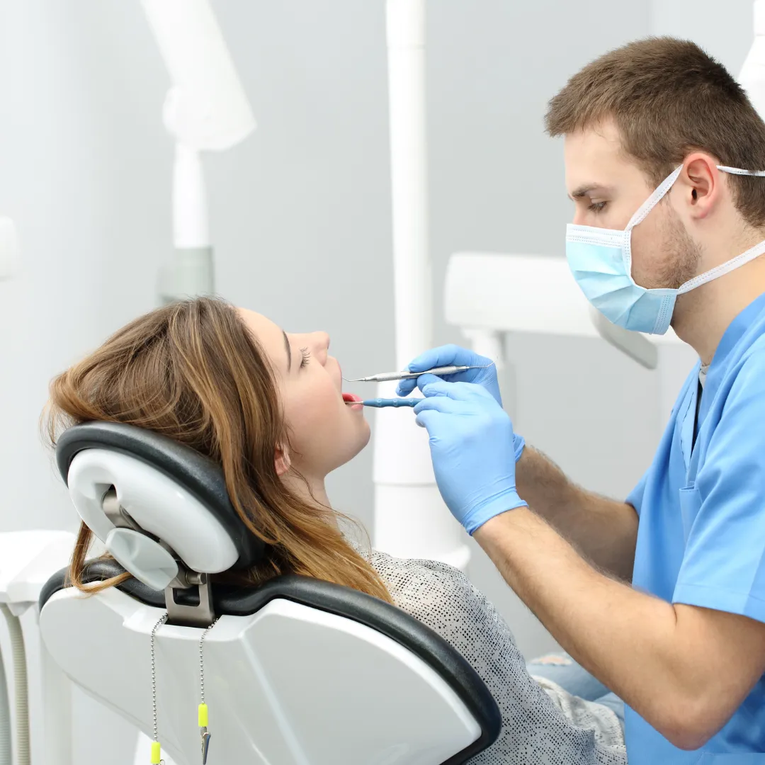 Patient receiving dental examination with tools in mouth, emphasizing dental care and health in a clinical setting.