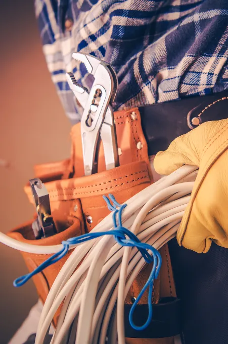 electrical rewiring man holding wires with a tool belt