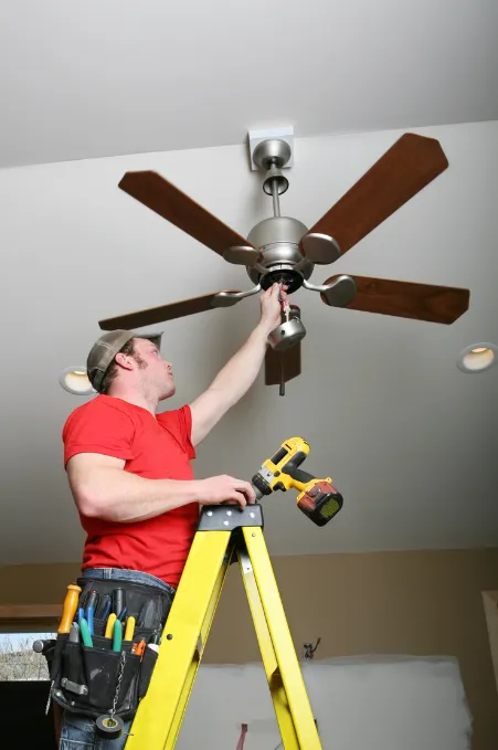 a man on a ladder doing a ceiling fan installation