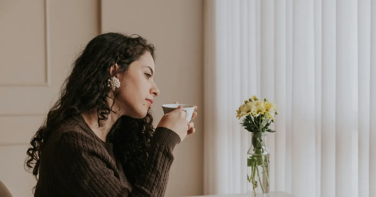 Woman in a calm interior space, composed and clear-eyed in soft natural light