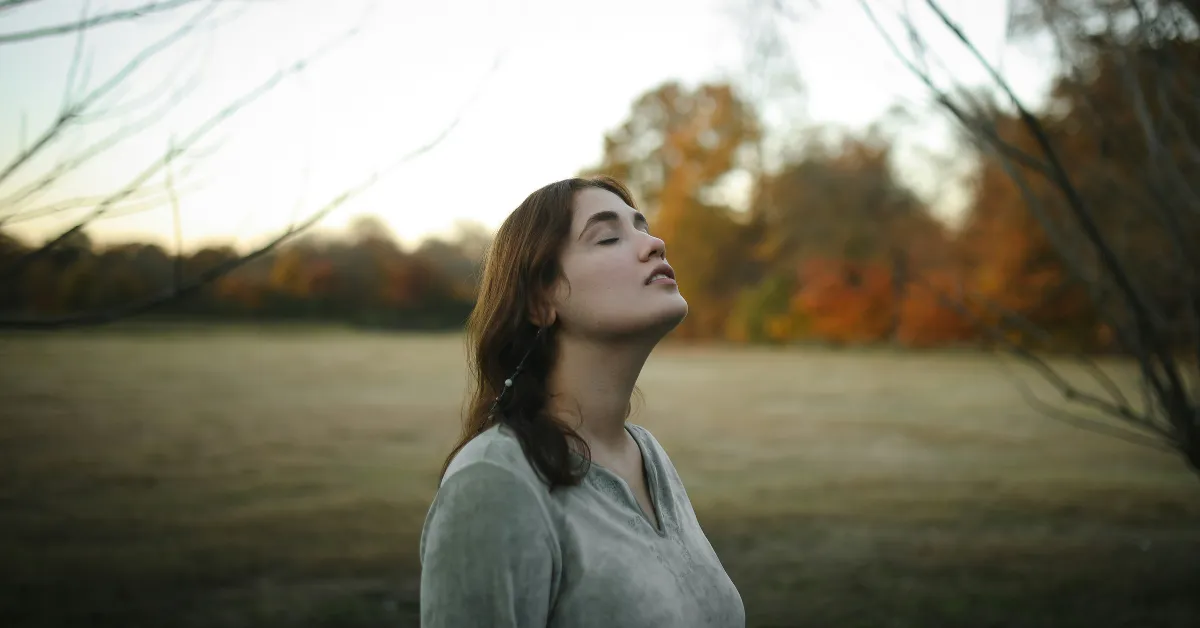 Woman sitting quietly by a window in soft natural light, in a moment of gentle self-reflection