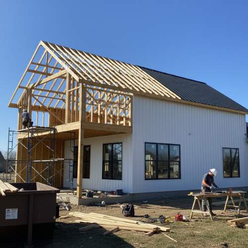 Half-completed barndominium with siding and roof, workers on site, for barndominium construction in olathe kansas
