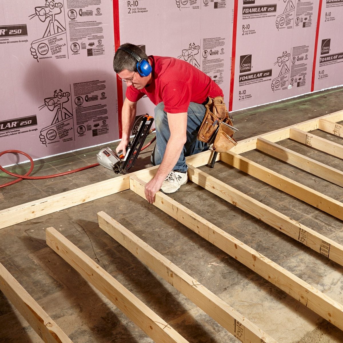 contractor in a red shirt builds wall studs in a basement, for basement finishing contractor olathe ks