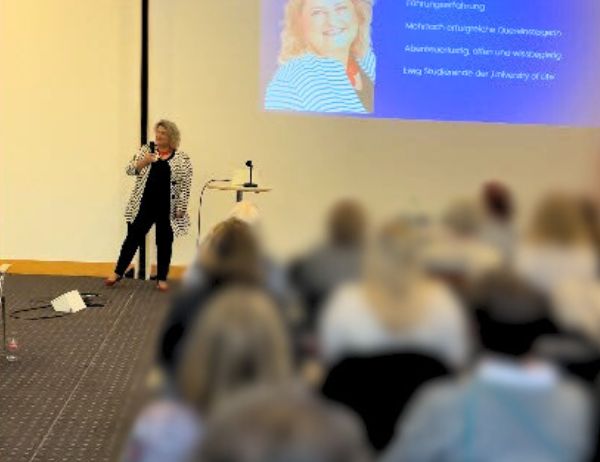 Birgit Gosejacob on stage with large projection screen showing her presentation