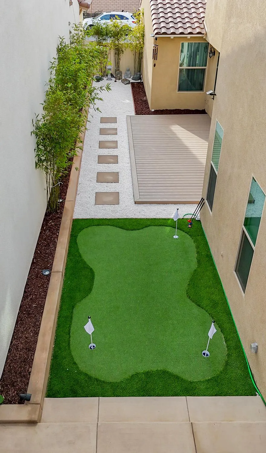 Backyard with a mini golf entertainment area, deck, and white river rocks