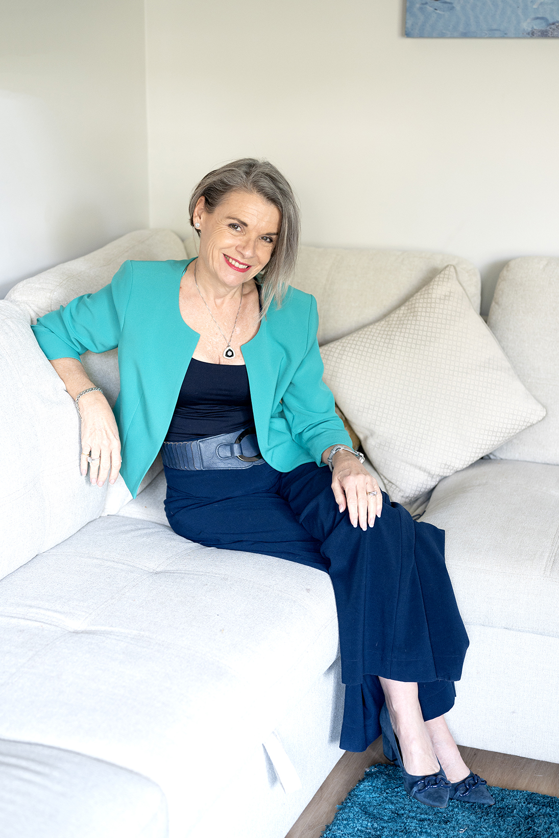 Ann Whitaker sitting in a purple and pink dress, holding a cup with her two dogs beside her.