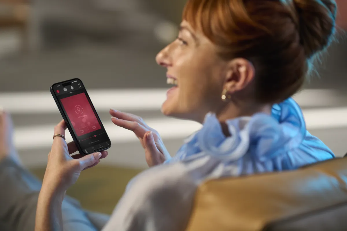 A smartphone interface showing an audio app over a dark red background with sound waves.