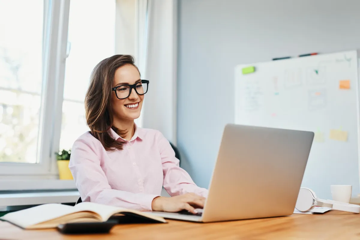 Woman smiling at laptop while sitting at a table
