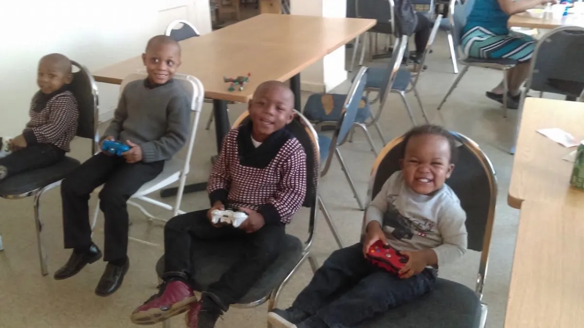 Students sit in a semicircle watching the teacher on a laptop