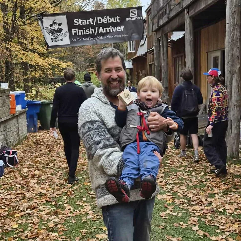 Race director Mike Caldwell holding 2.5-year-old Asher, the youngest finisher at the Mad Trapper trail race near Ottawa in Denholm Quebec