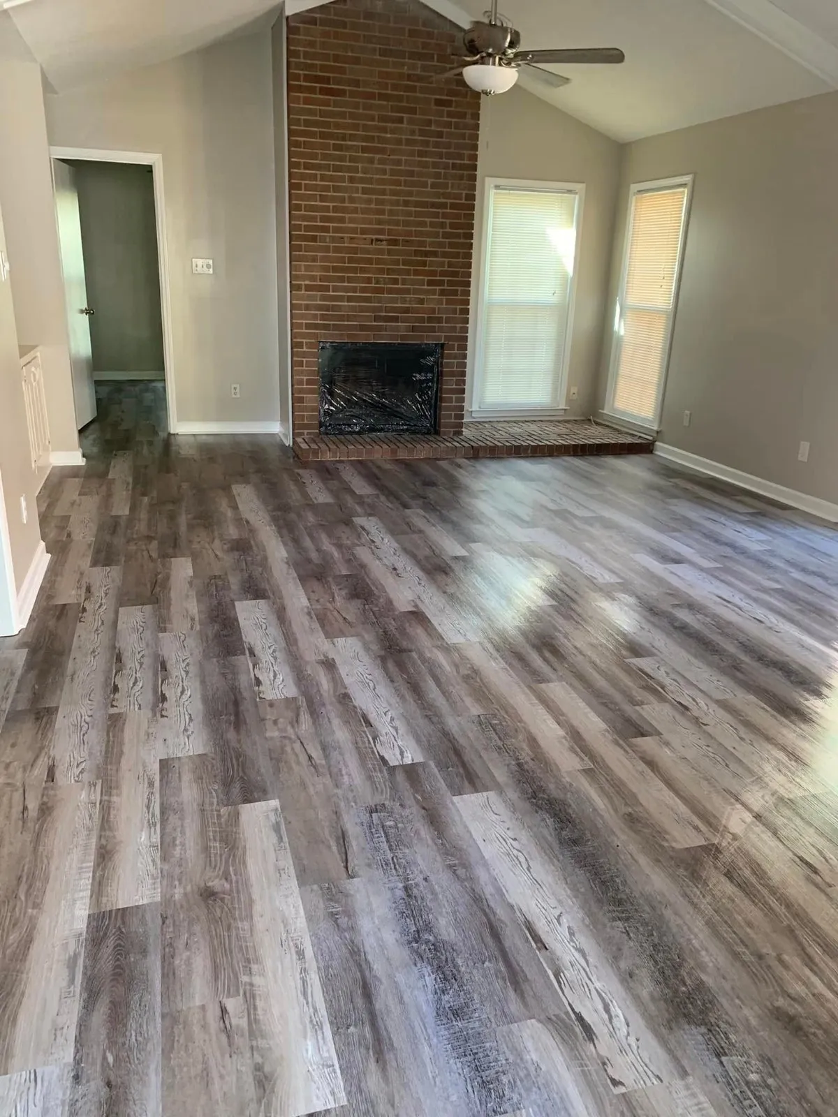 Brick fireplace and plank floors in a living room cleaned by Pretty in Pink Cleaning Service in Wetumpka, AL