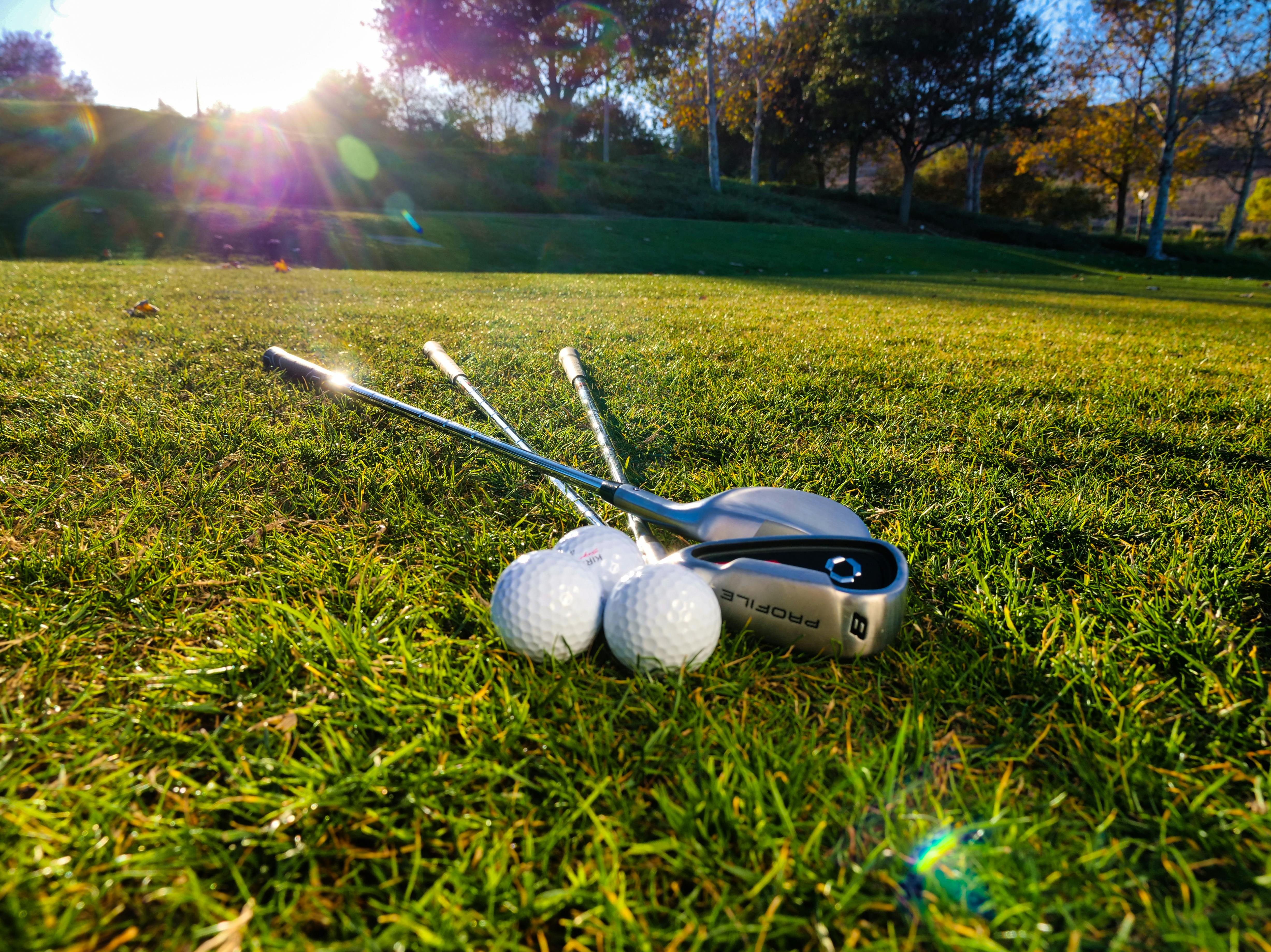 Golf clubs and balls on grass with sunlight