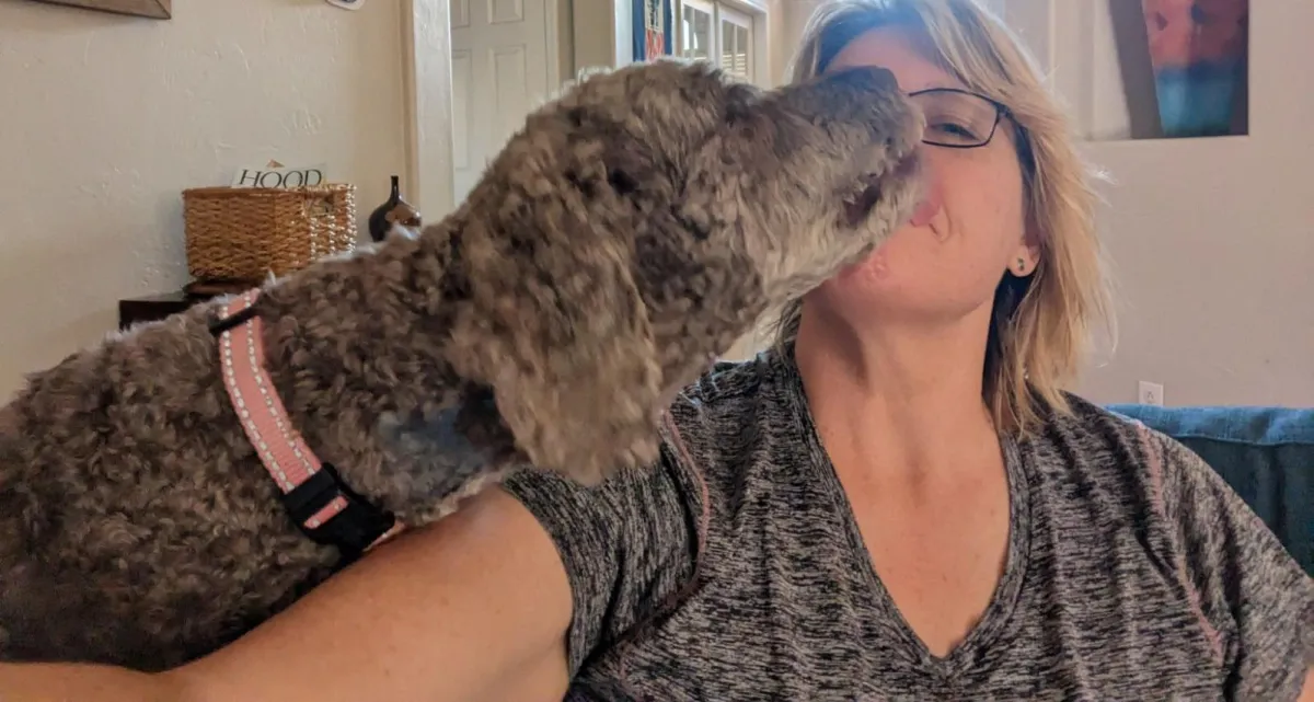 Sherry being kissed by her dog