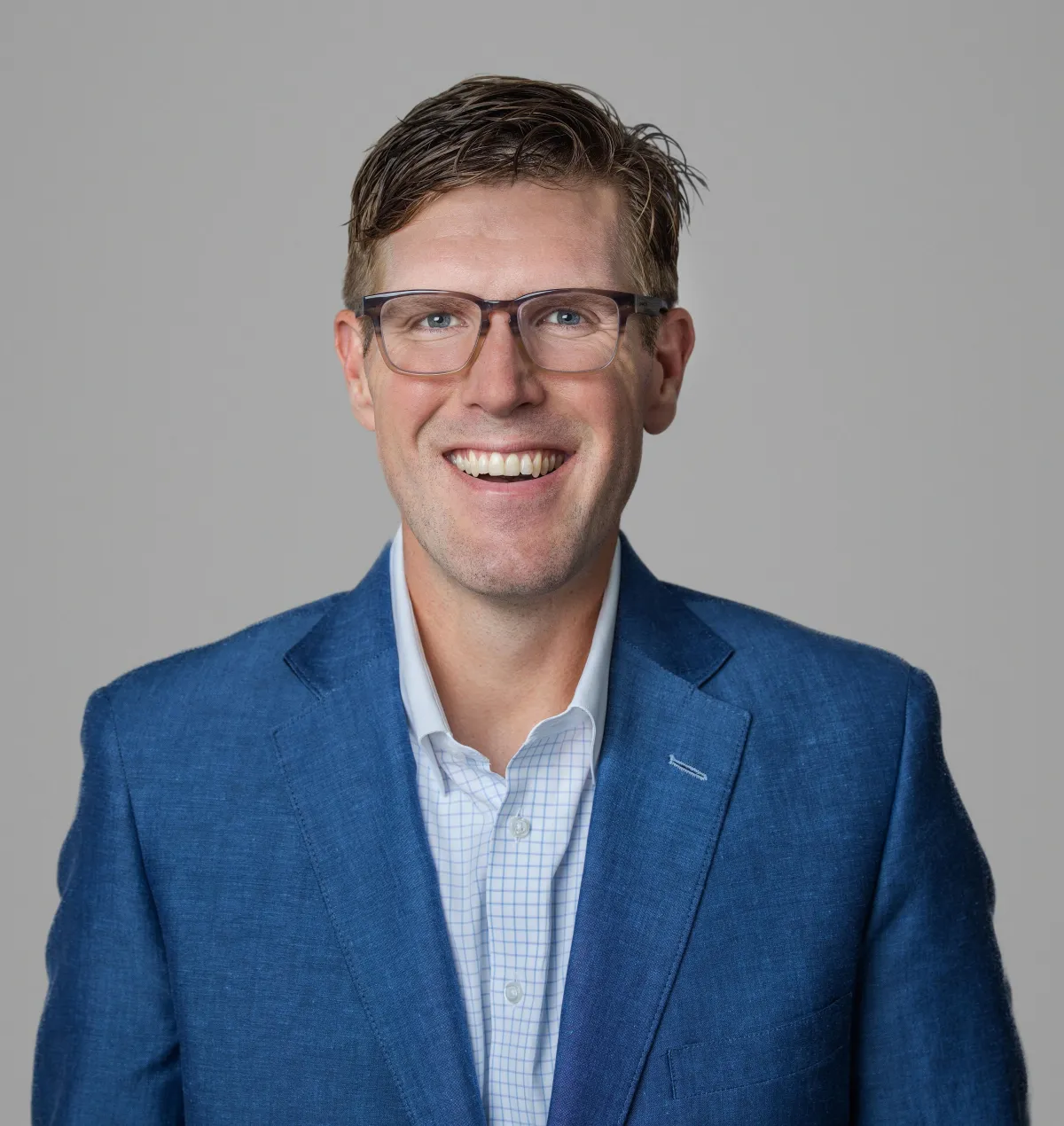 four people all on laptops, two men and two women, listen to person talking in a board meeting