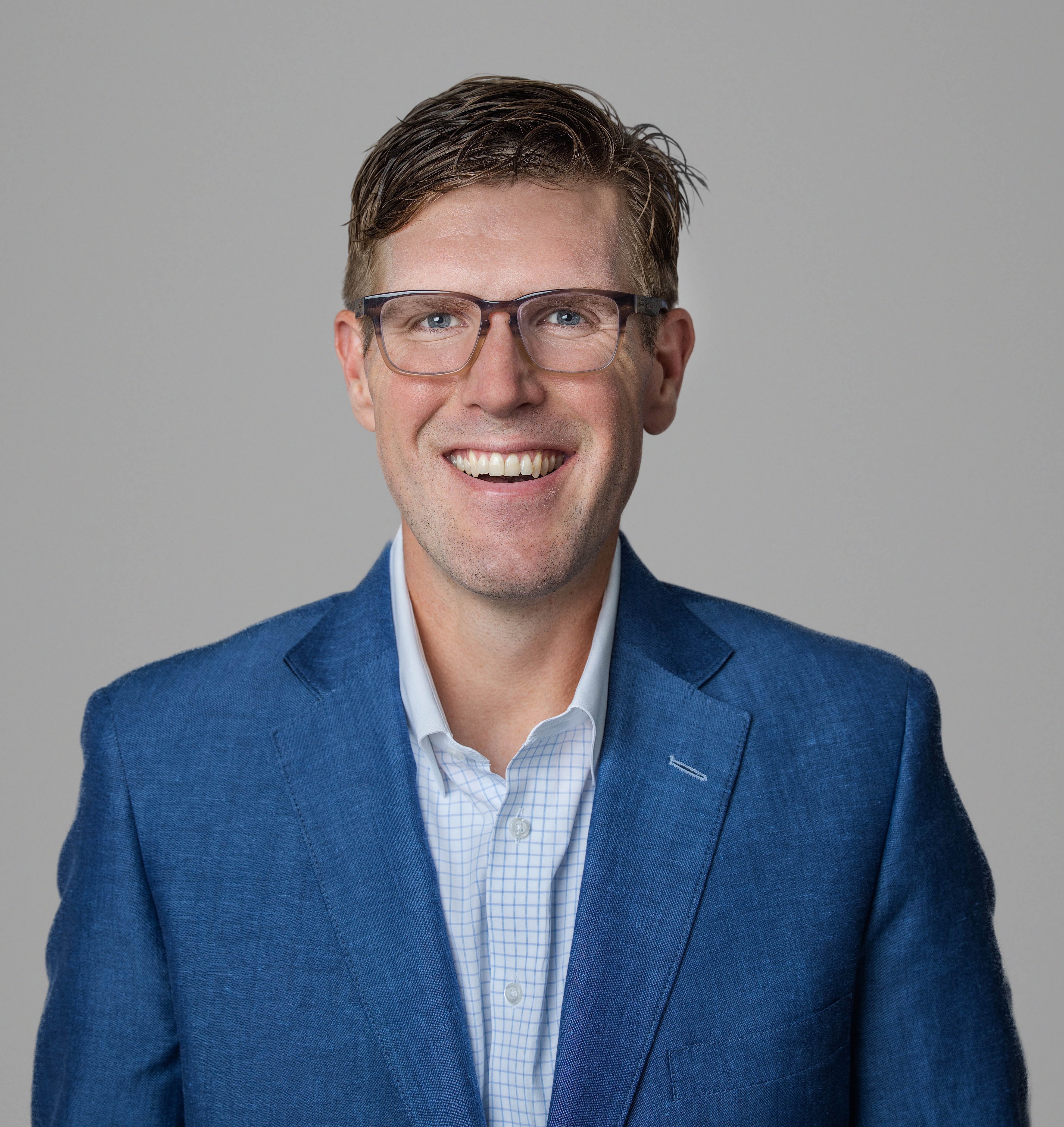 four people all on laptops, two men and two women, listen to person talking in a board meeting
