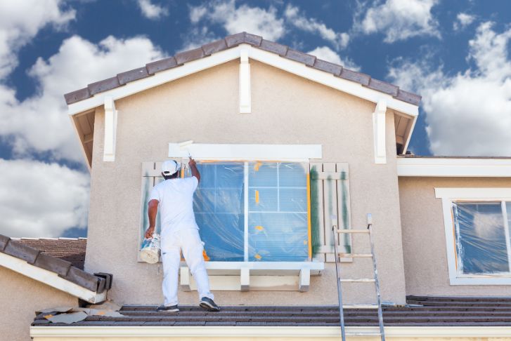 pic of a worker painting trim of a house
