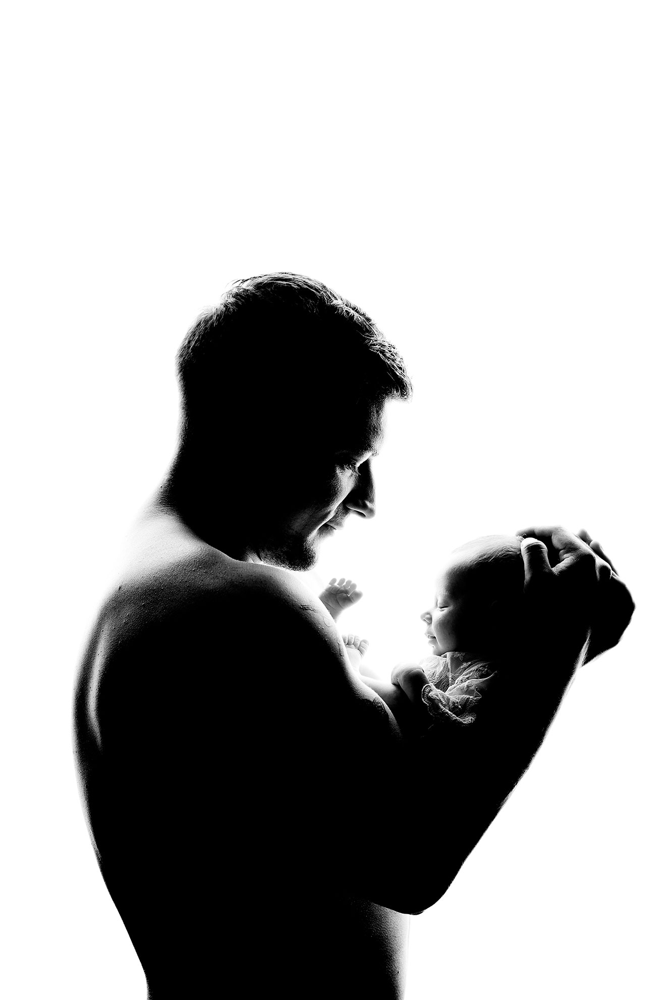 Father looking down at newborn baby resting on chest