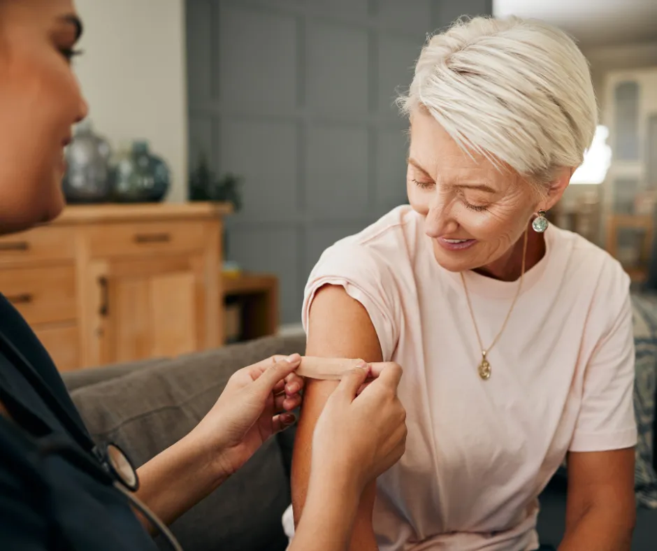 Healthcare provider placing a bandage on a smiling patient's arm after a vaccination.