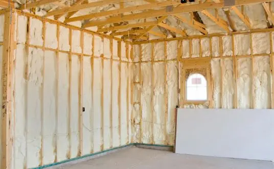 Garage walls and ceiling filled with spray foam between wood studs, drywall stacked and ready, by Perth Amboy Spray Foam Insulation