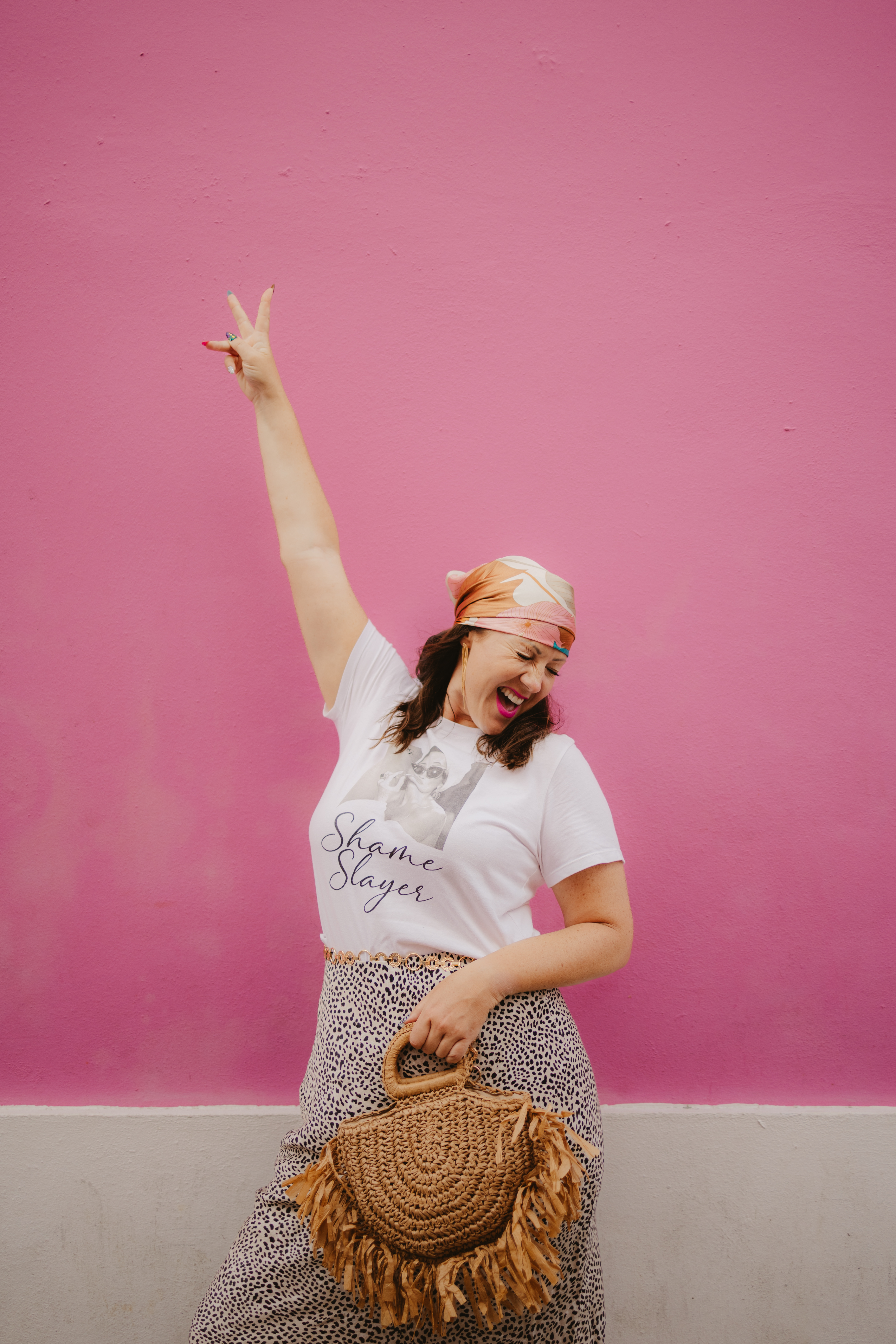 Naomi Morgan wearing a Shame Slayer t-shirt against a pink wall