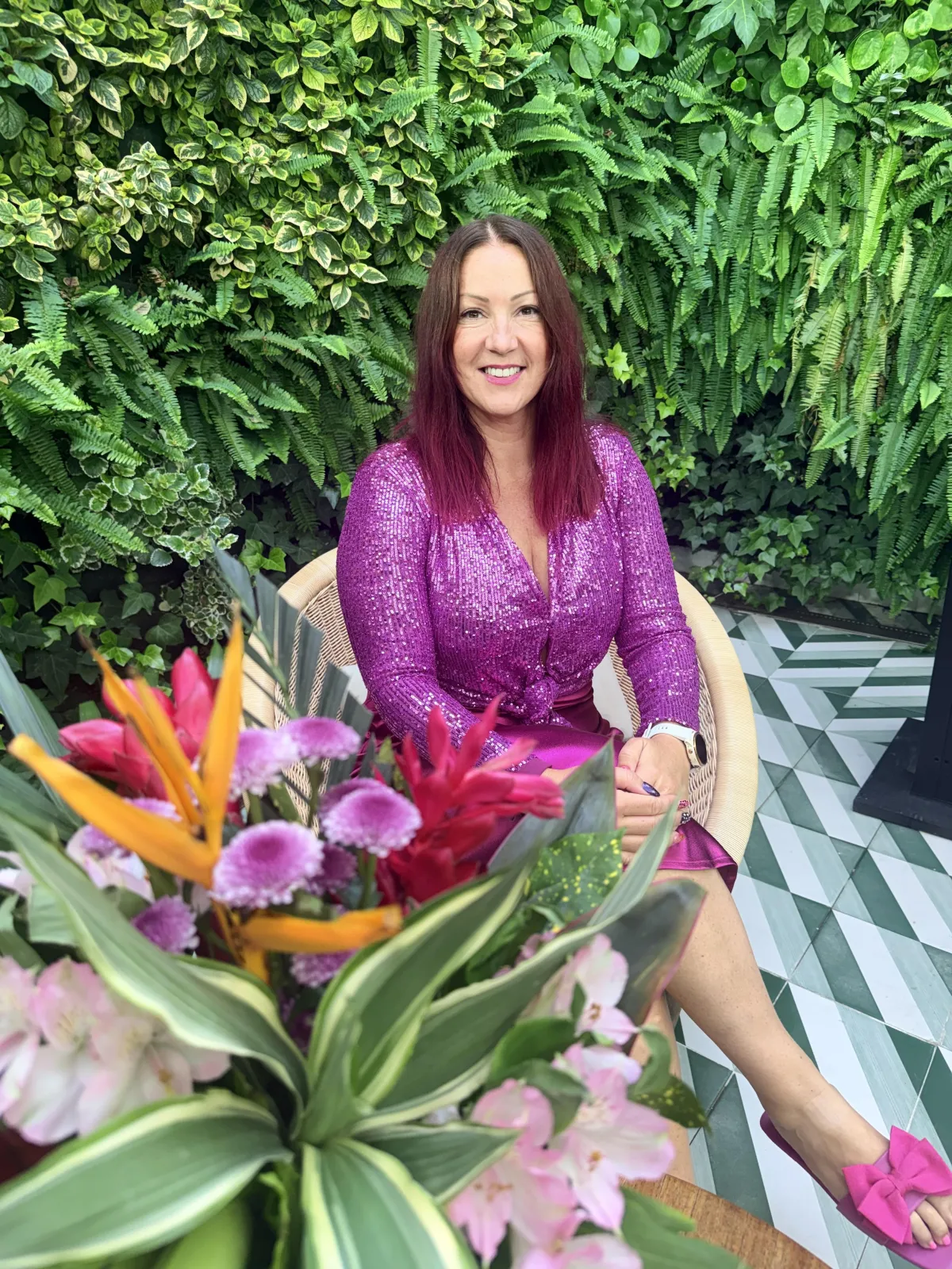Naomi Morgan smiling against a green fern wall