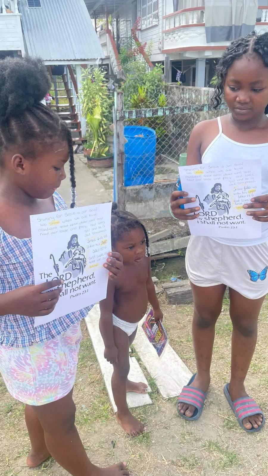 Children holding Psalm 23 printouts in a Rosignol neighborhood