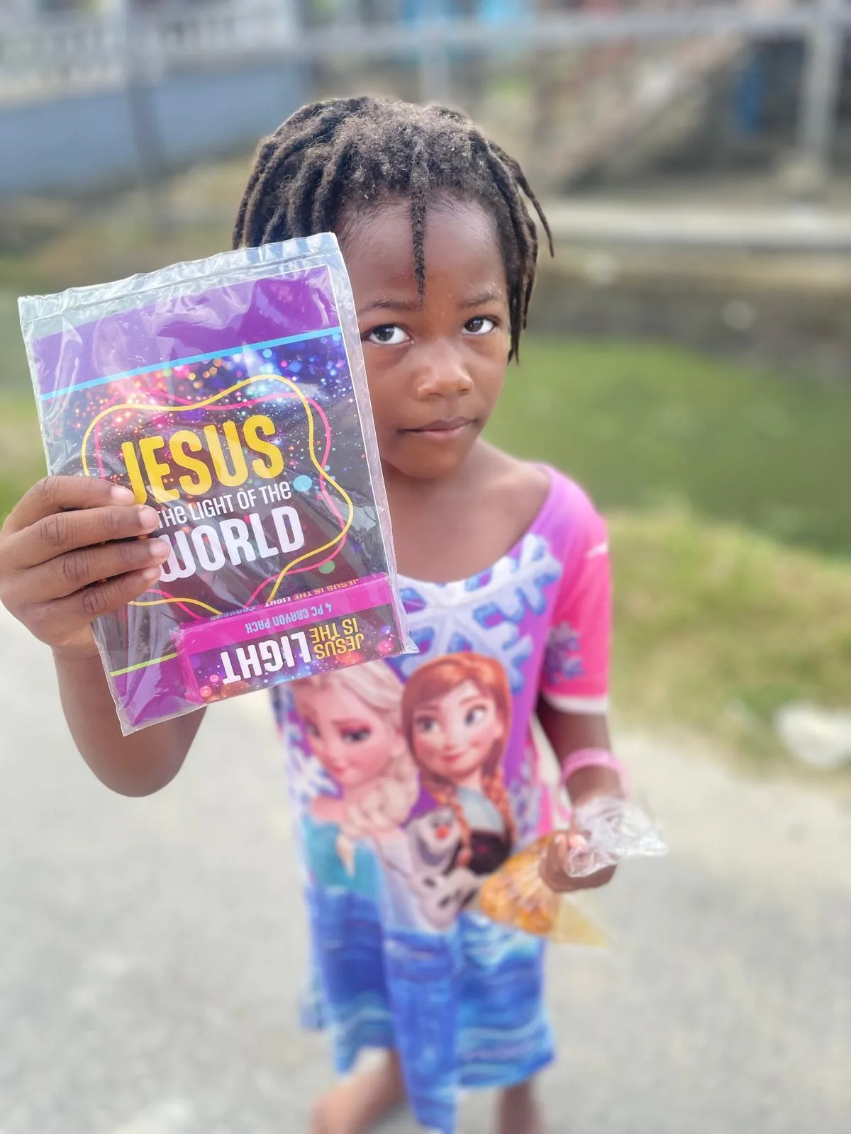 A girl holding a Jesus is the Light of the World pamphlet and a bag of treats